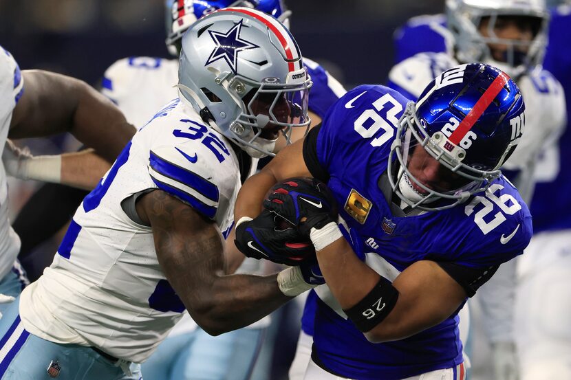 Saquon Barkley #26 of the New York Giants wrestles for the ball against Rashaan Evans #32 of...