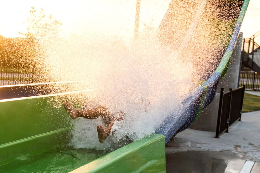 Ashtin Majacot, 11, of McKinney, splashes into water while riding a slide during a pool...