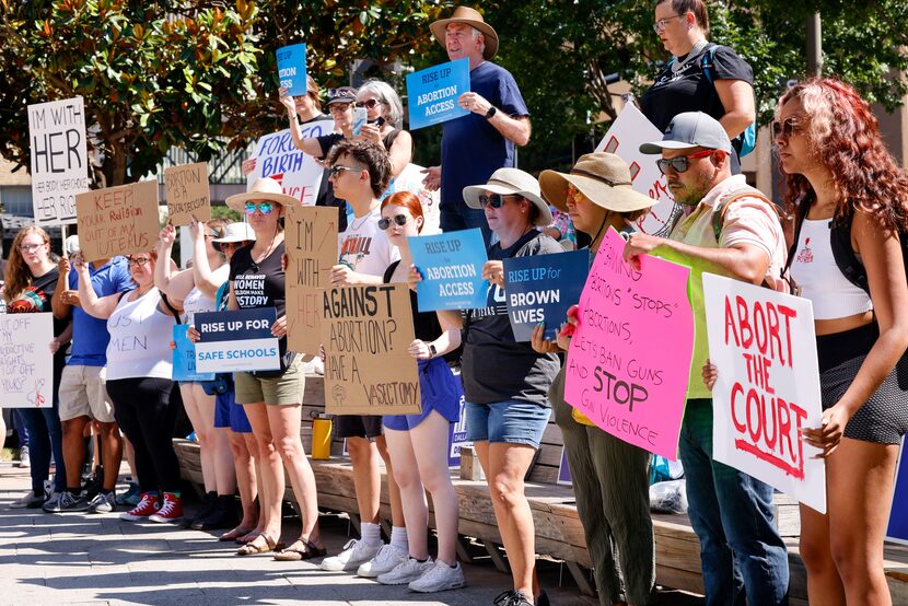 Abortion-rights supporters carry signs on stage behind a speaker during a rally at Main...