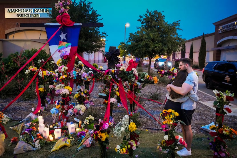 A couple embraces at a growing memorial outside the mall a day after a mass shooting at...