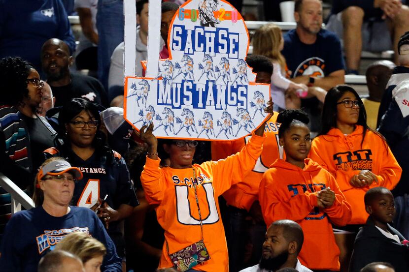 A sachse fan holds up a sign in the stands before the start of the first half of a high...