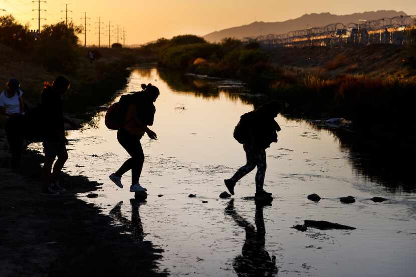 A migrant group steps across stones in the Rio Grande to get to the U.S. side at Gate 42 in...