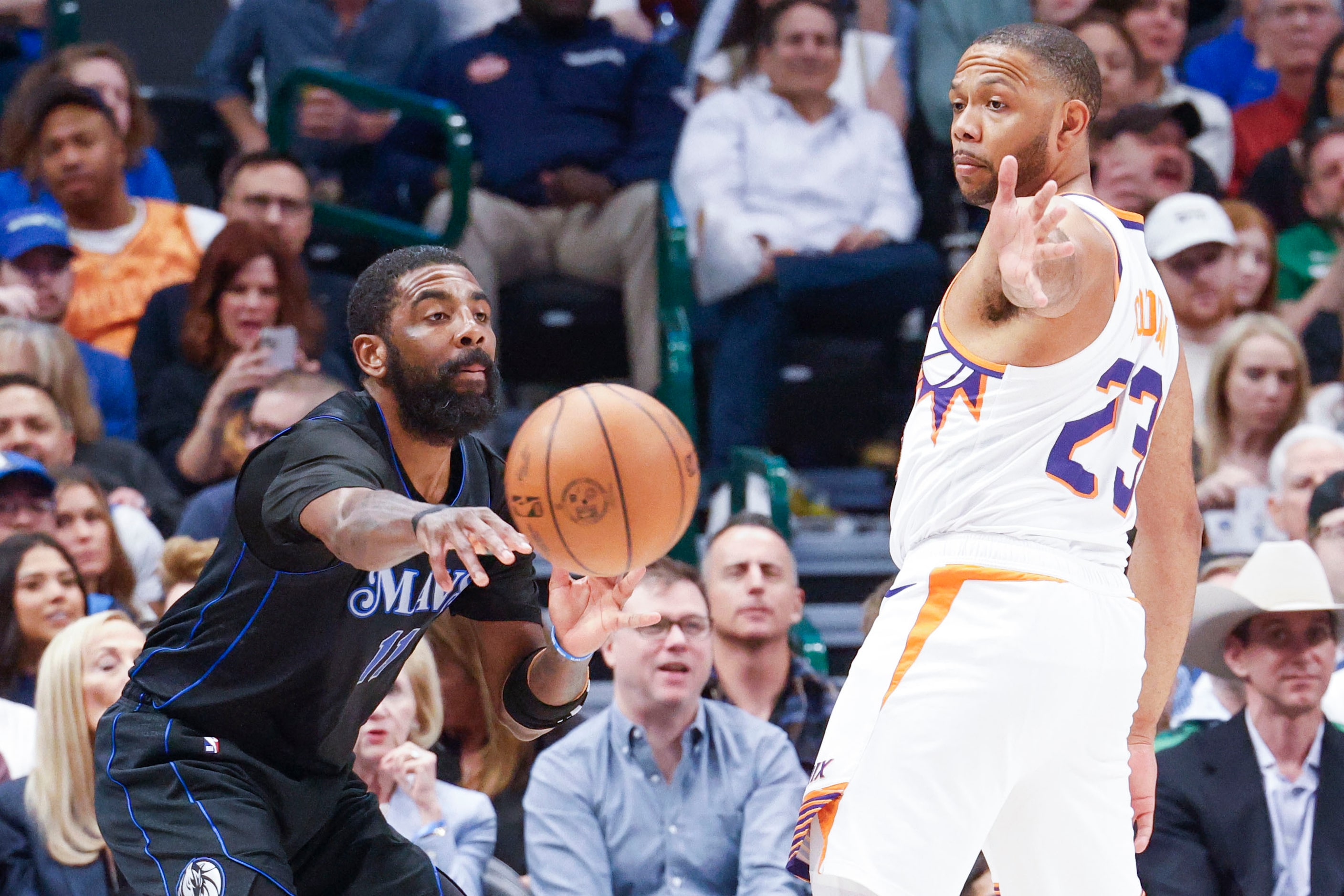 Dallas Mavericks guard Kyrie Irving (left) passes as Phoenix Suns guard Eric Gordon reaches...