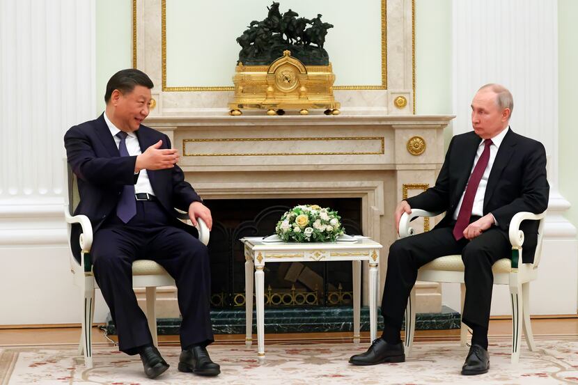 Chinese President Xi Jinping gestures as he speaks to Russian President Vladimir Putin...
