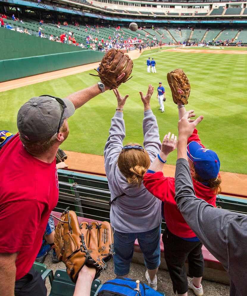 
Fans reached for a ball tossed into the stands as the Rangers took batting practice before...