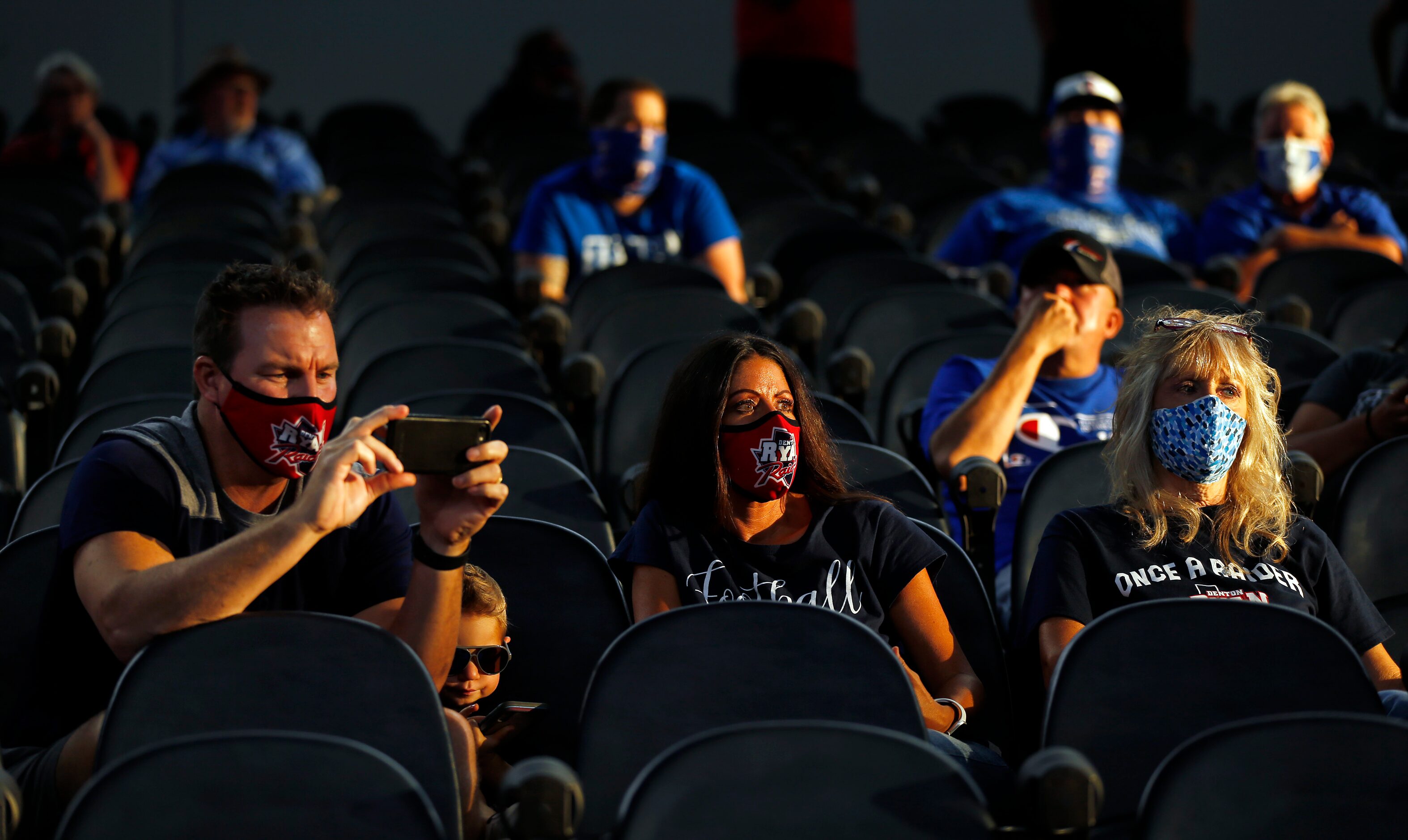 Socially distanced Denton Ryan football fans watch their team face Arlington Martin during...