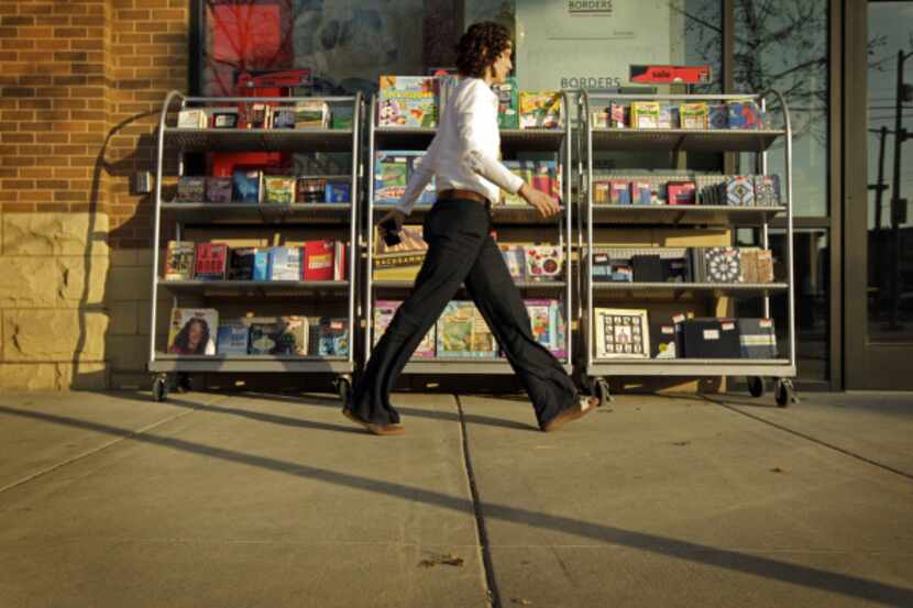 A passer-by walked in front of sales racks full of books outside the West Village Borders on...