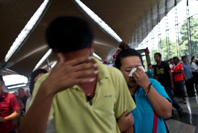 A woman breaks down while leaving the reception center for families and friends at Kuala...