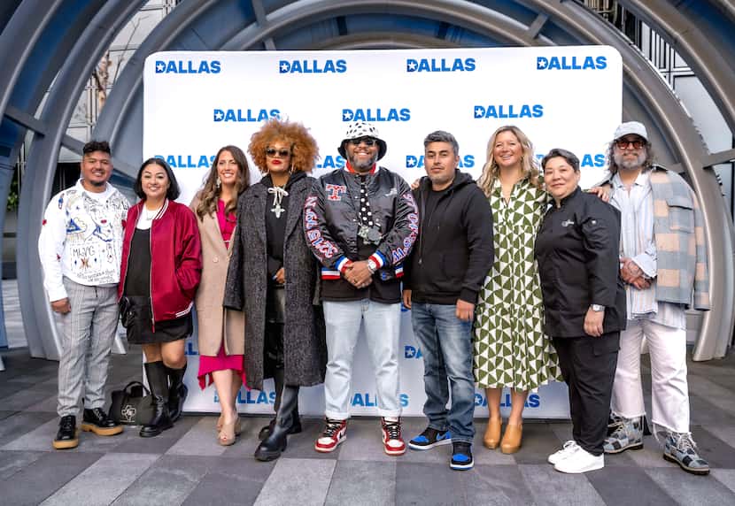 A diverse group of individuals posing together in front of a banner saying Dallas.