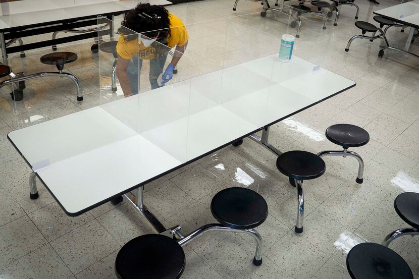 Custodian Debra Booty disinfects tables in the cafeteria at Paul L. Dunbar Learning Center...