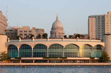 Swimmers pass in front of Monona Terrace in Madison as the Wisconsin state capitol is seen...