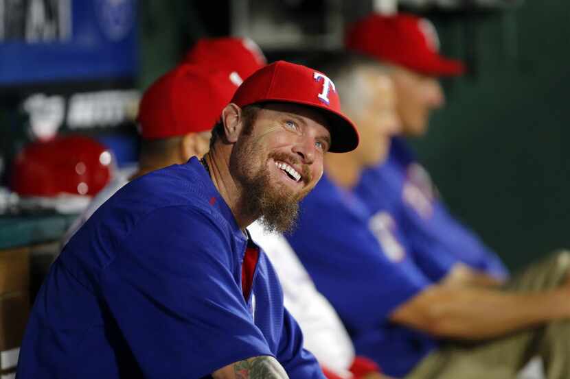 FILE - Texas Rangers Josh Hamilton smiles from the bench while talking to coaches  in the...