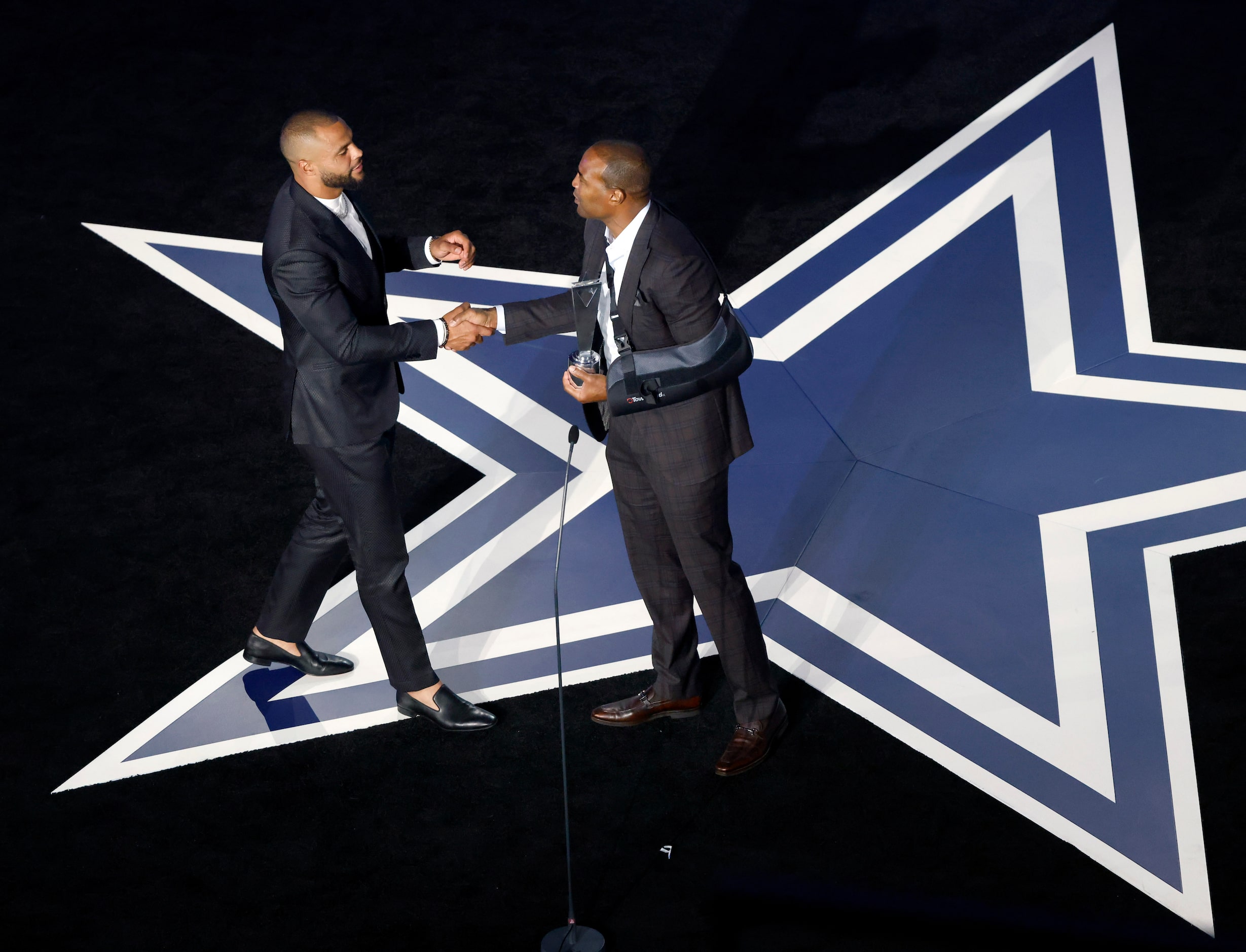 Former Dallas Cowboys players Darren Woodson (right) presents current Cowboys quarterback...