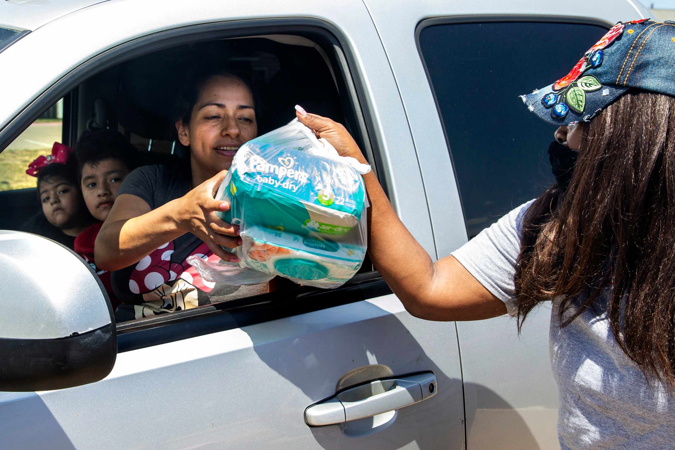 President and founder Alexandrea Crutcher-Horsley (right) hands diapers to Xochitl Zuniga...