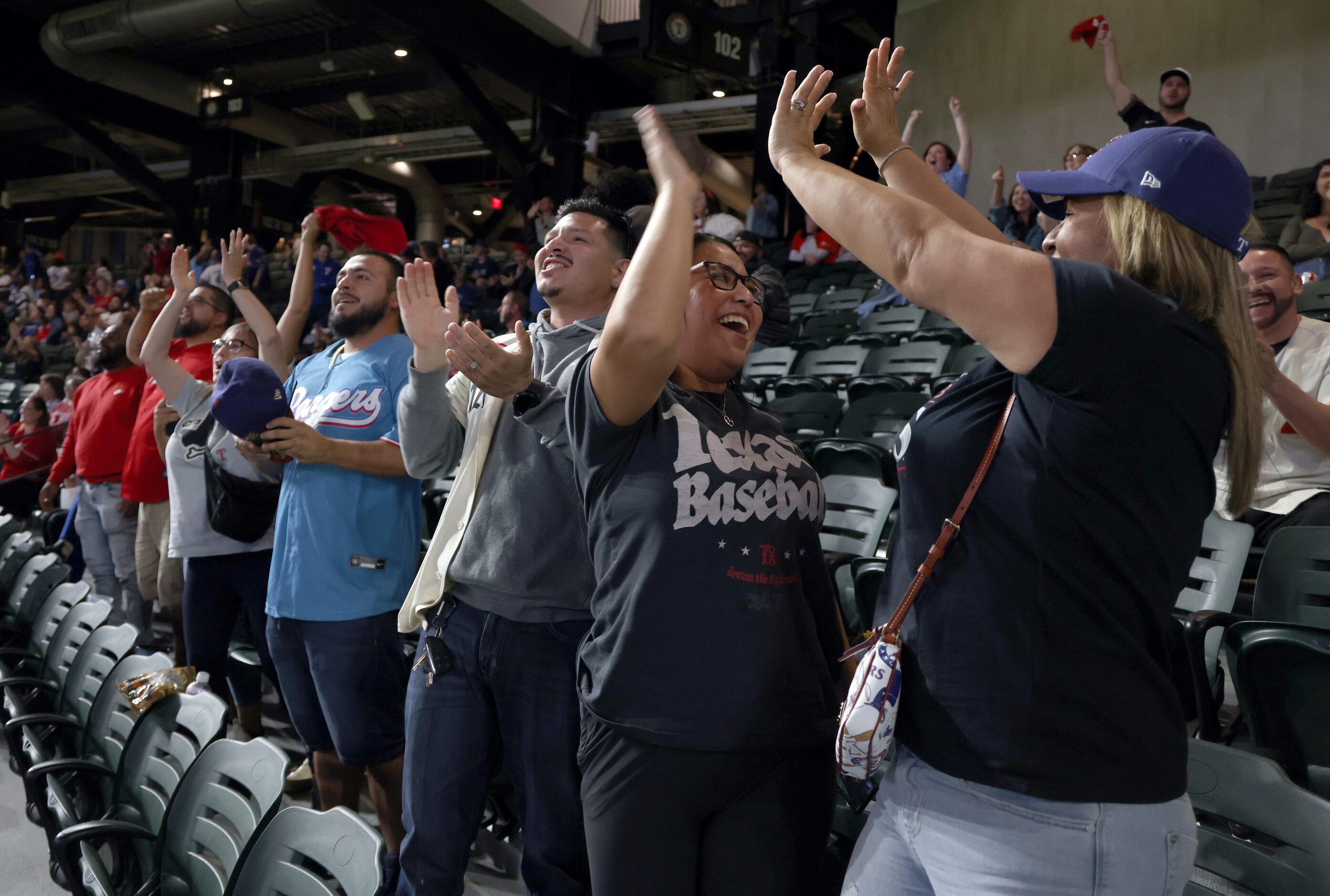 Texas Rangers fans Erica Lara, right, and Cassie Rodriguez, 2nd from right, exchange high...