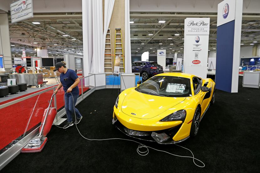 Norma Ayala vacuums the show floor next to the 2017 McLaren 570S Coupe at the DFW Auto Show...