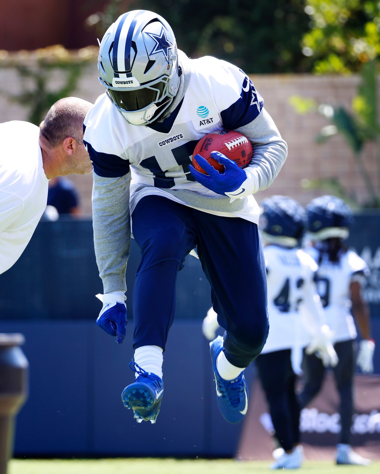 Dallas Cowboys running back Ezekiel Elliott (15) leaps past a blocking pad during a training...