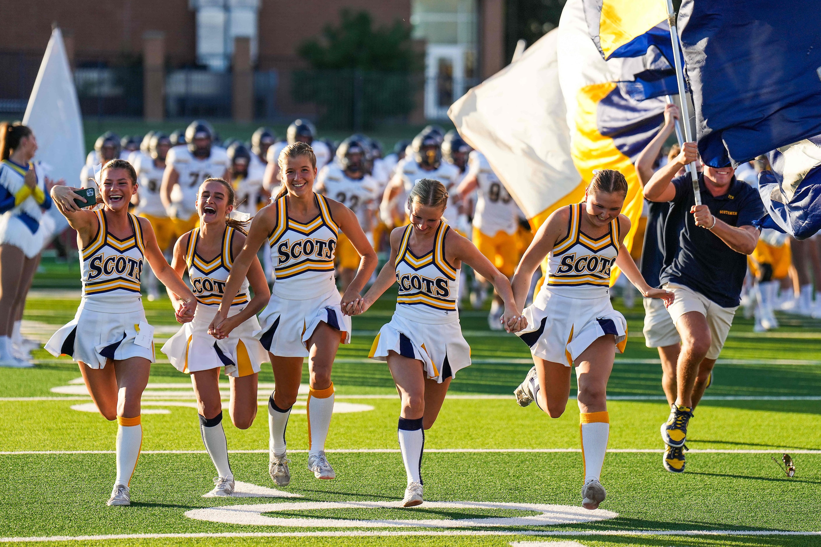 Highland Park cheerleaders lead the team as they take the field for the first half of a high...