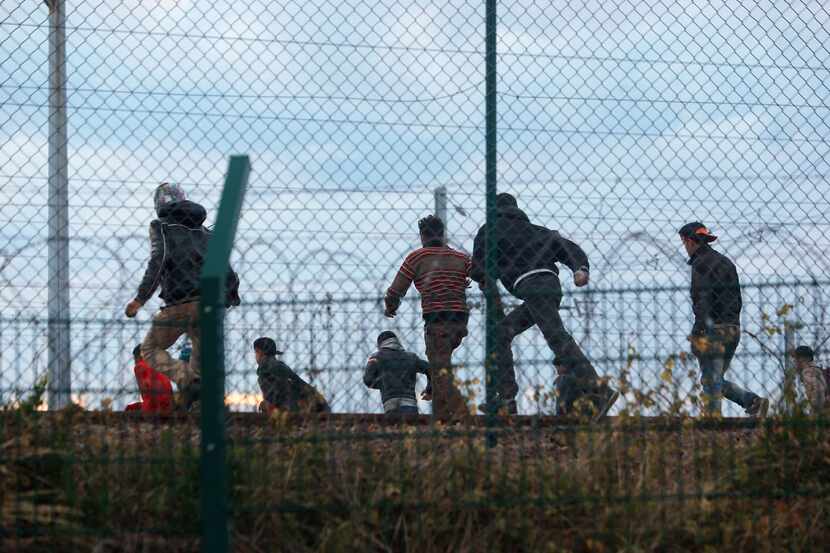 Migrants run on the railway as they attempt to access the Channel Tunnel in Calais. Migrants...