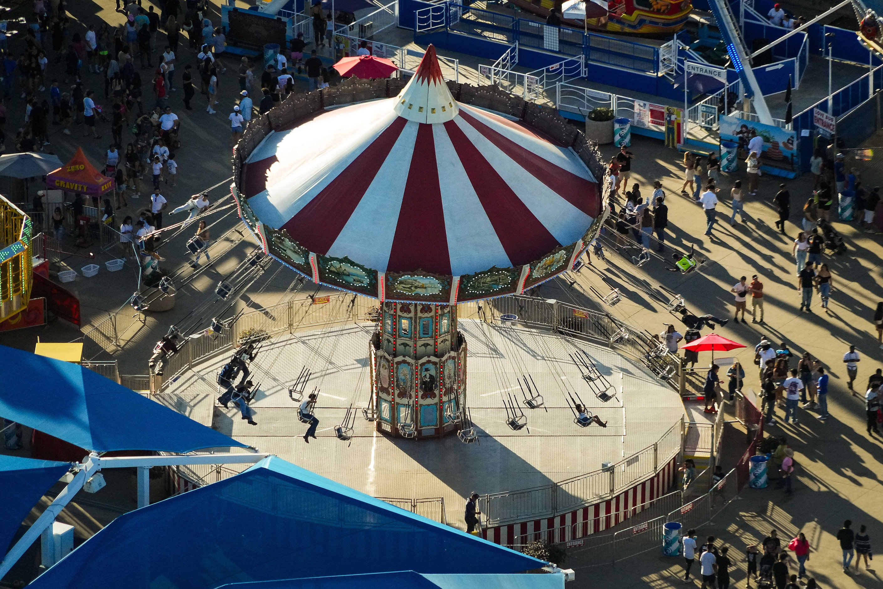 Fairgoers ride the Wave Swinger ride on the midway at the State Fair of Texas on Sunday,...