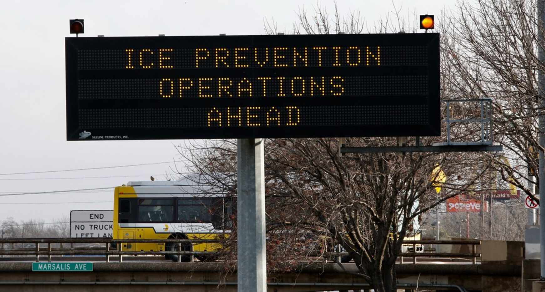 Commuters drive by a sign warning them to watch for work crews doing ice prevention on...