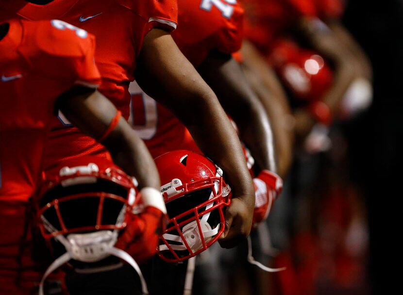 Helmets in hand, the Skyline football team lines up for the national anthem before facing...