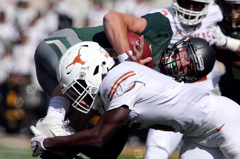Texas defensive back Holton Hill (5) upends Baylor quarterback Charlie Brewer in the first...