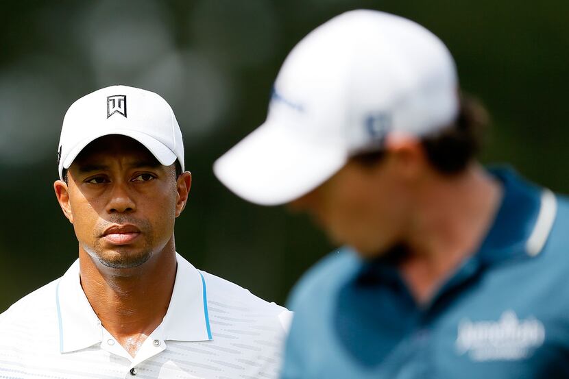 Tiger Woods (L) and Rory McIlroy of Northern Ireland walk off the fourth green during the...