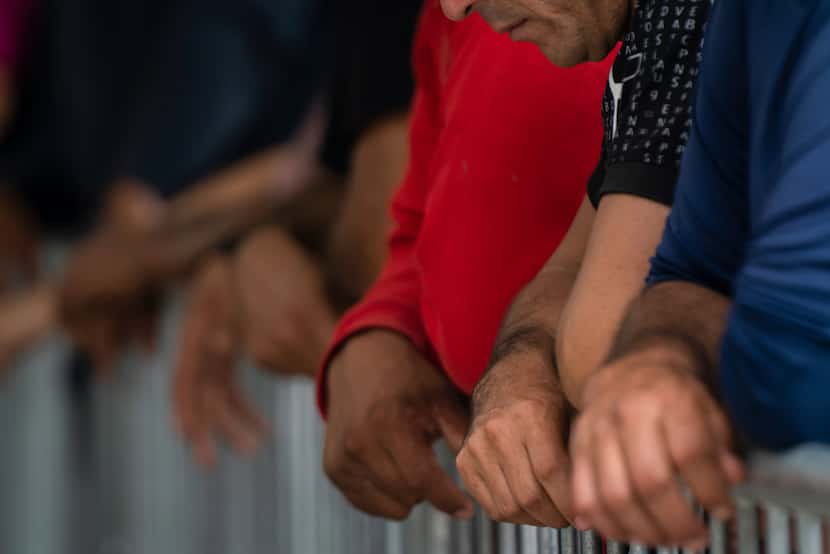 FILE - Migrants wait at the Gateway International Port of Entry under U.S. Customs and...