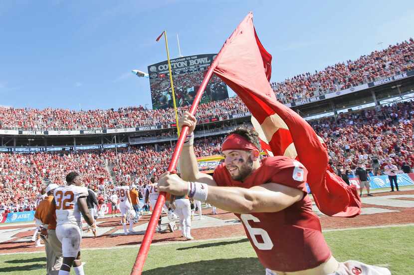 Oklahoma quarterback Baker Mayfield (6) runs on the field with a school flag after 45-40 win...