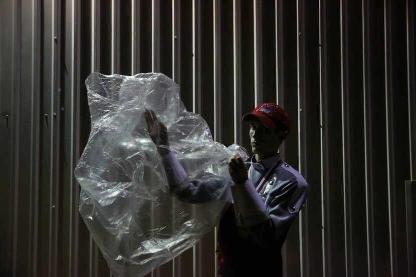 McKinney Boyd band member Cody Norman, 17, puts on a rain poncho as halftime approaches...