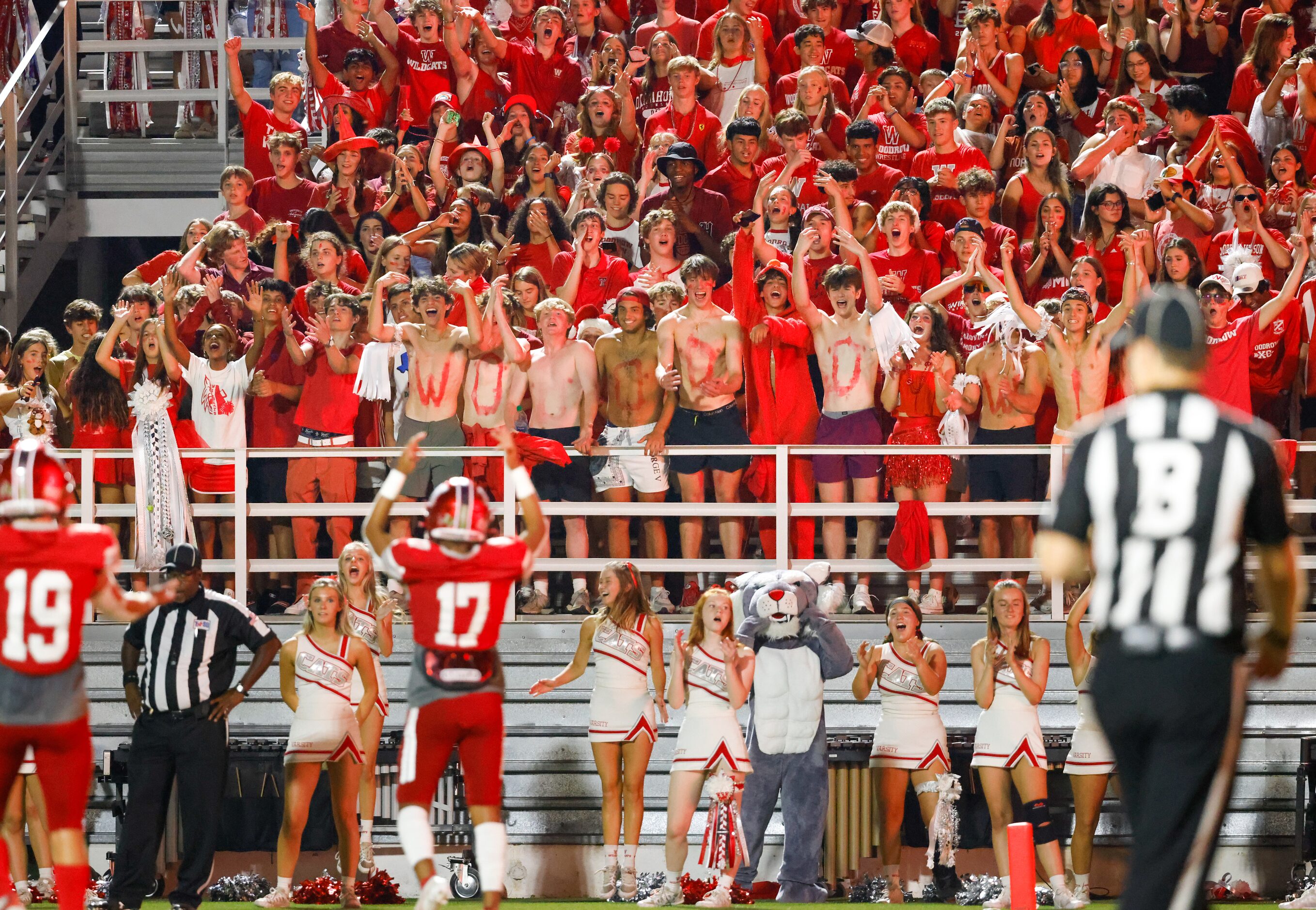 Woodrow Wilson High School students and fans cheer for their team in response to line backer...