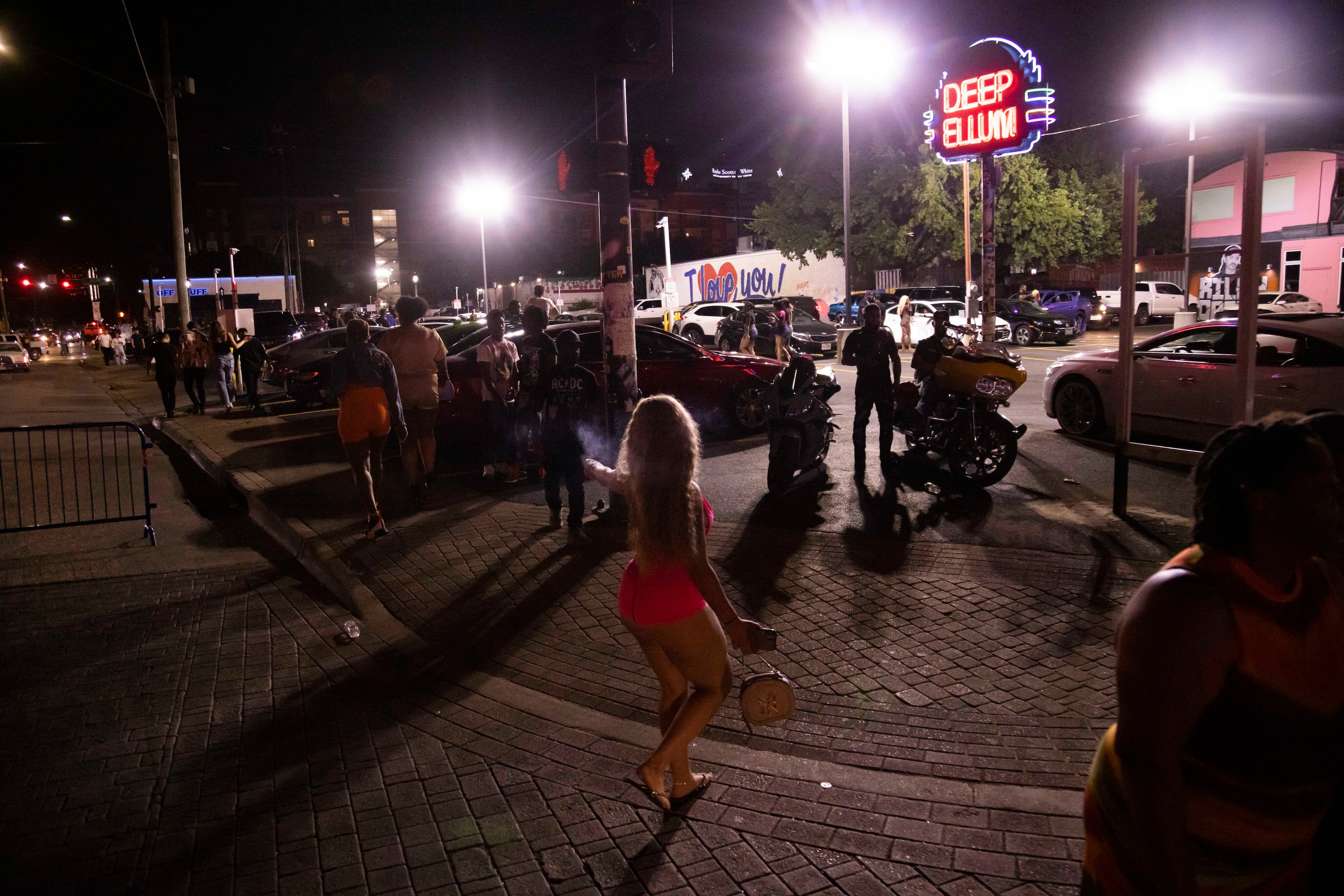 People walk in the streets as bars begin to close in the Deep Ellum district of Dallas on...