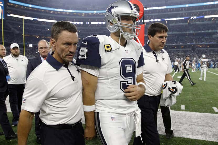 Team staff escort Dallas Cowboys quarterback Tony Romo (9) off the field after Romo suffered...