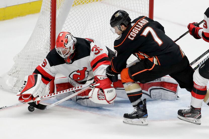 New Jersey Devils goaltender Cory Schneider, left, blocks a shot by Anaheim Ducks left wing...