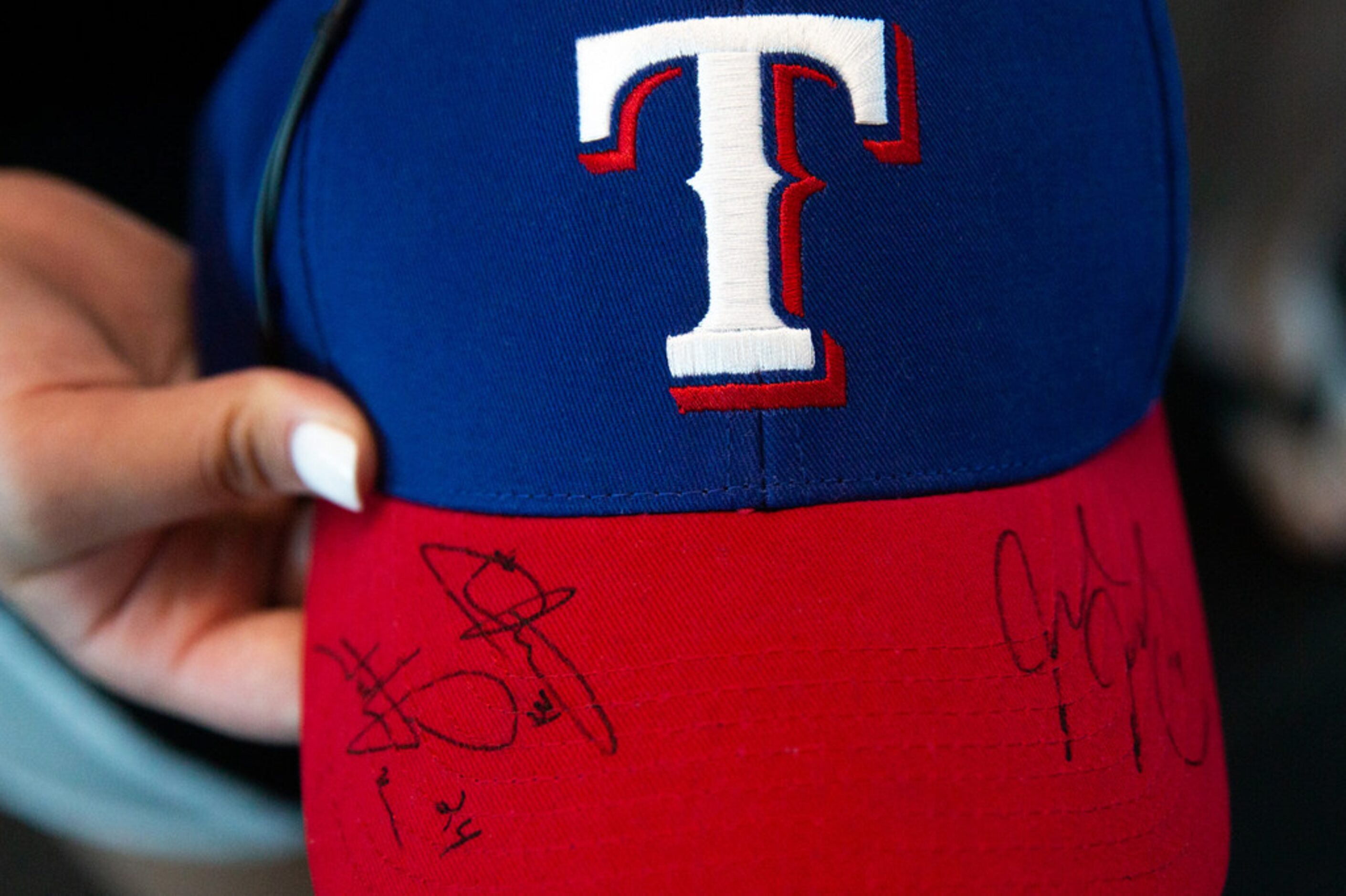 Katie Chappell, 14, holds up her signed Texas Rangers hat after players autographed it...