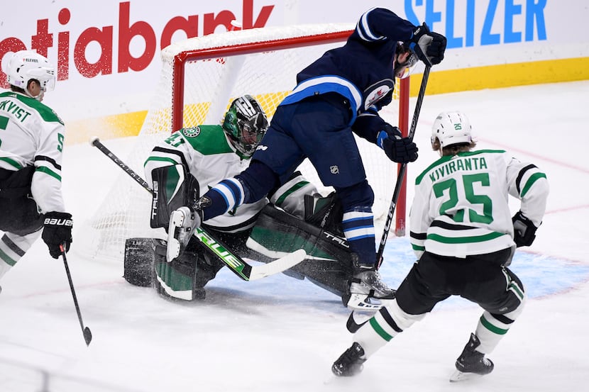 Winnipeg Jets' Jansen Harkins (12) collides with Dallas Stars' goaltender Scott Wedgewood...