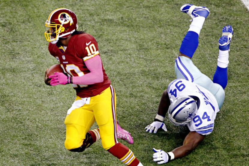 Washington Redskins quarterback Robert Griffin III (10) evades a tackle by Dallas Cowboys...