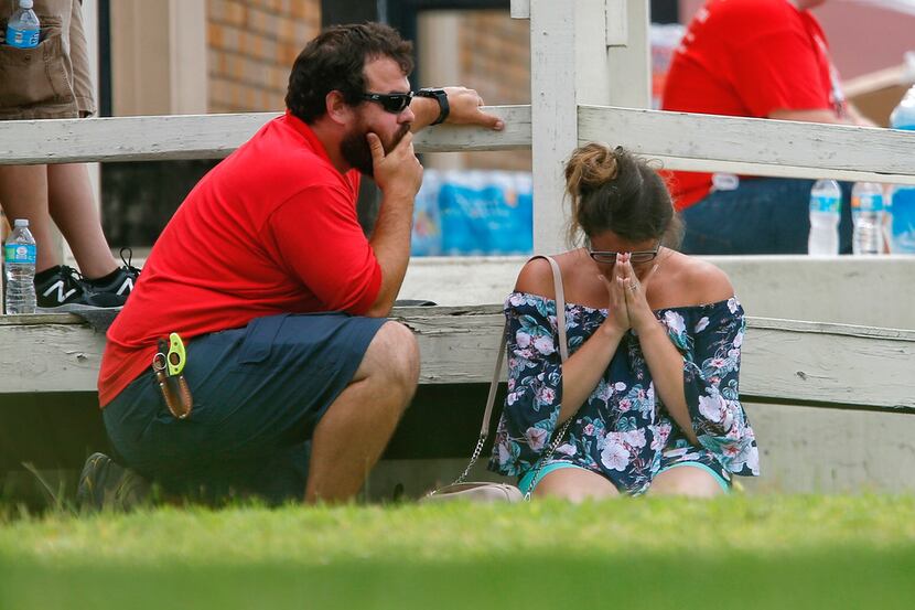 A woman prays in the grass outside the Alamo Gym where parents wait to reunite with their...