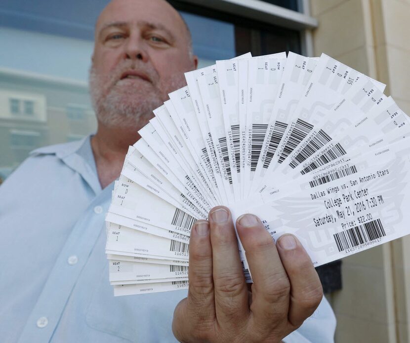 Stephen Watkins, a Dallas Wings season ticket holder, poses for a photograph holding his...