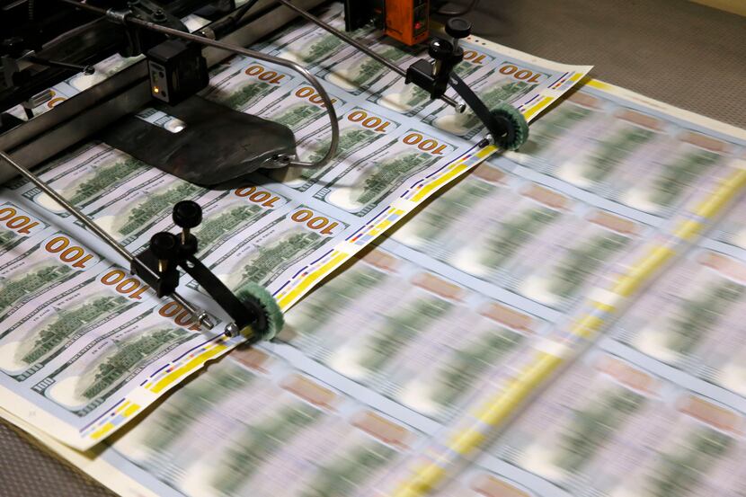 $100 notes feed through the printer at the Bureau of Engraving and Printing in Fort Worth on...