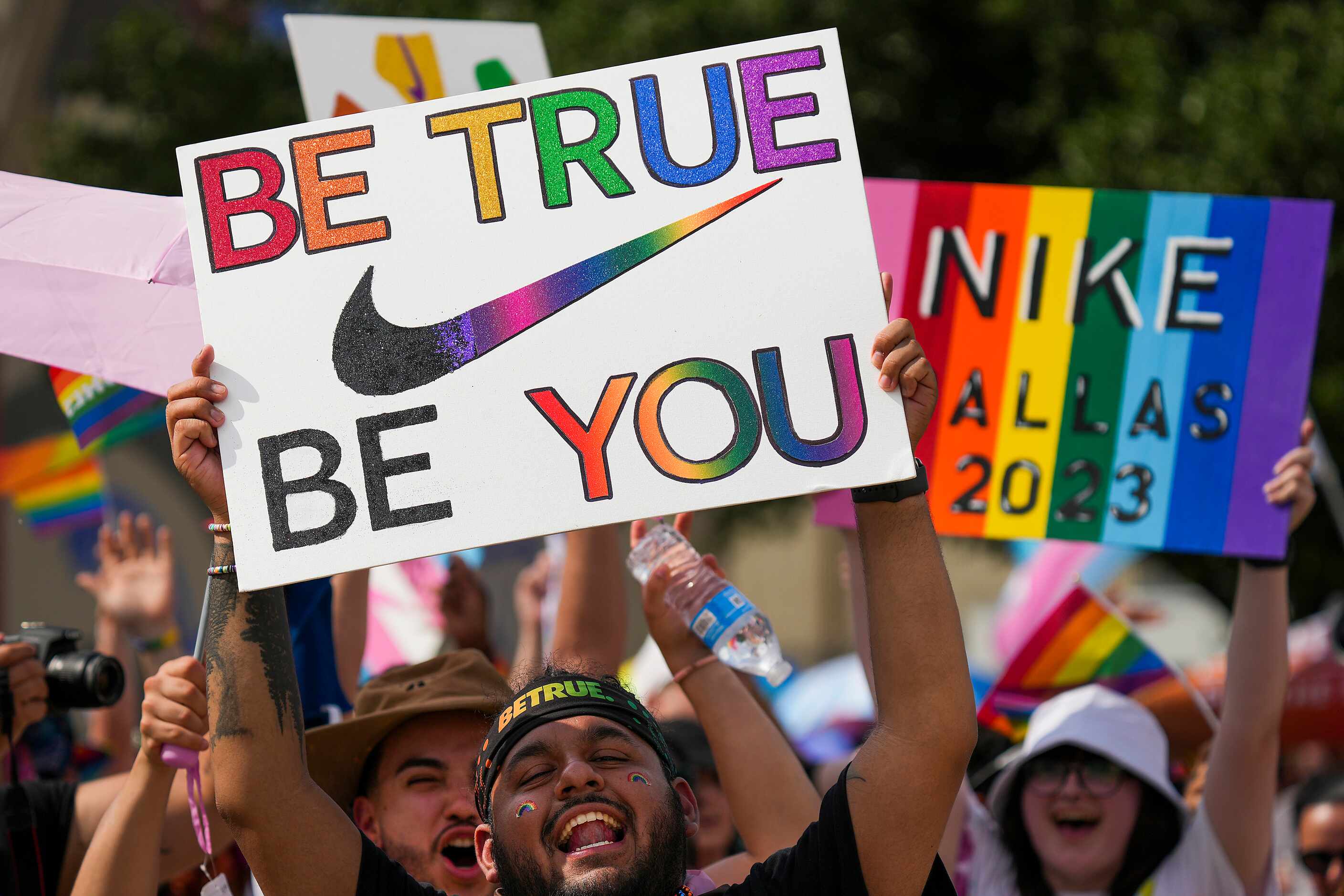 A participant with a group from Nike holds a sign reading “Be True Be You” during the annual...