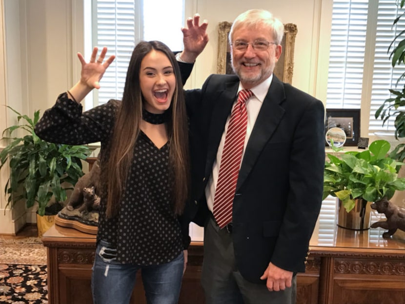 Incoming freshman Julianna Comstock and interim President David Garland make a bear claw....