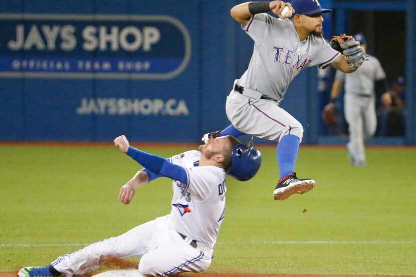 Toronto's Josh Donaldson, left, takes a knee to the head as Texas Rangers second baseman...