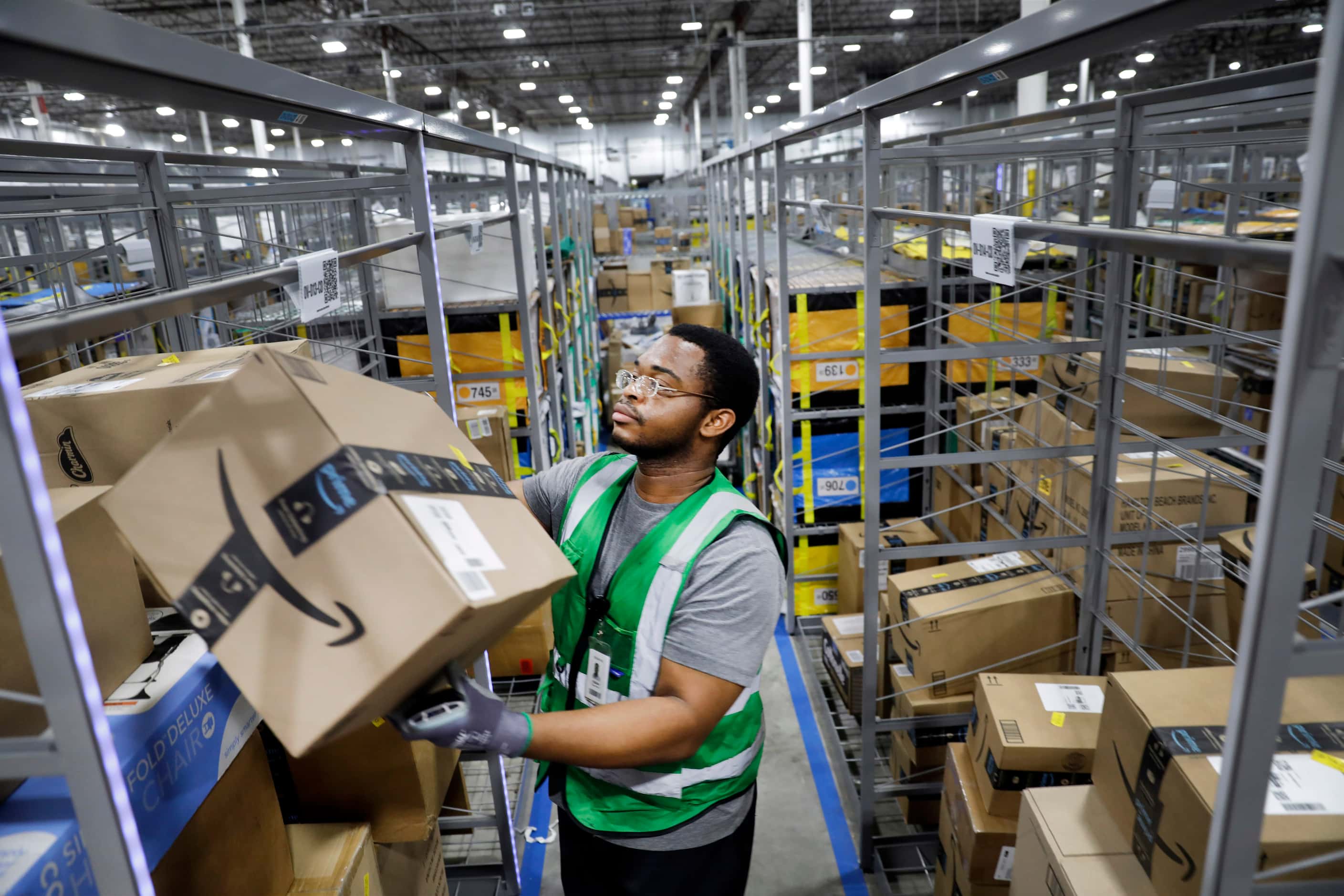 Crew member Fabian Ugwunwa stows early PRIME day deal packages onto shelves and totes for...