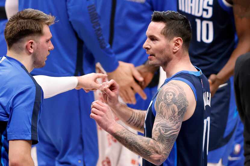 Dallas Mavericks guard JJ Redick (right) receives some pointers from teammate Luka Doncic...