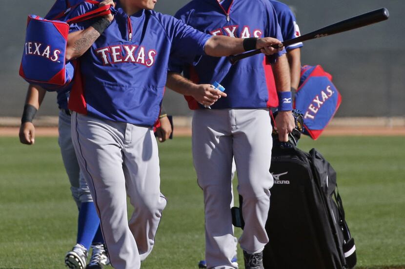 Texas outfielder Shin-Soo Choo talks with teammates as they walk across the field on their...