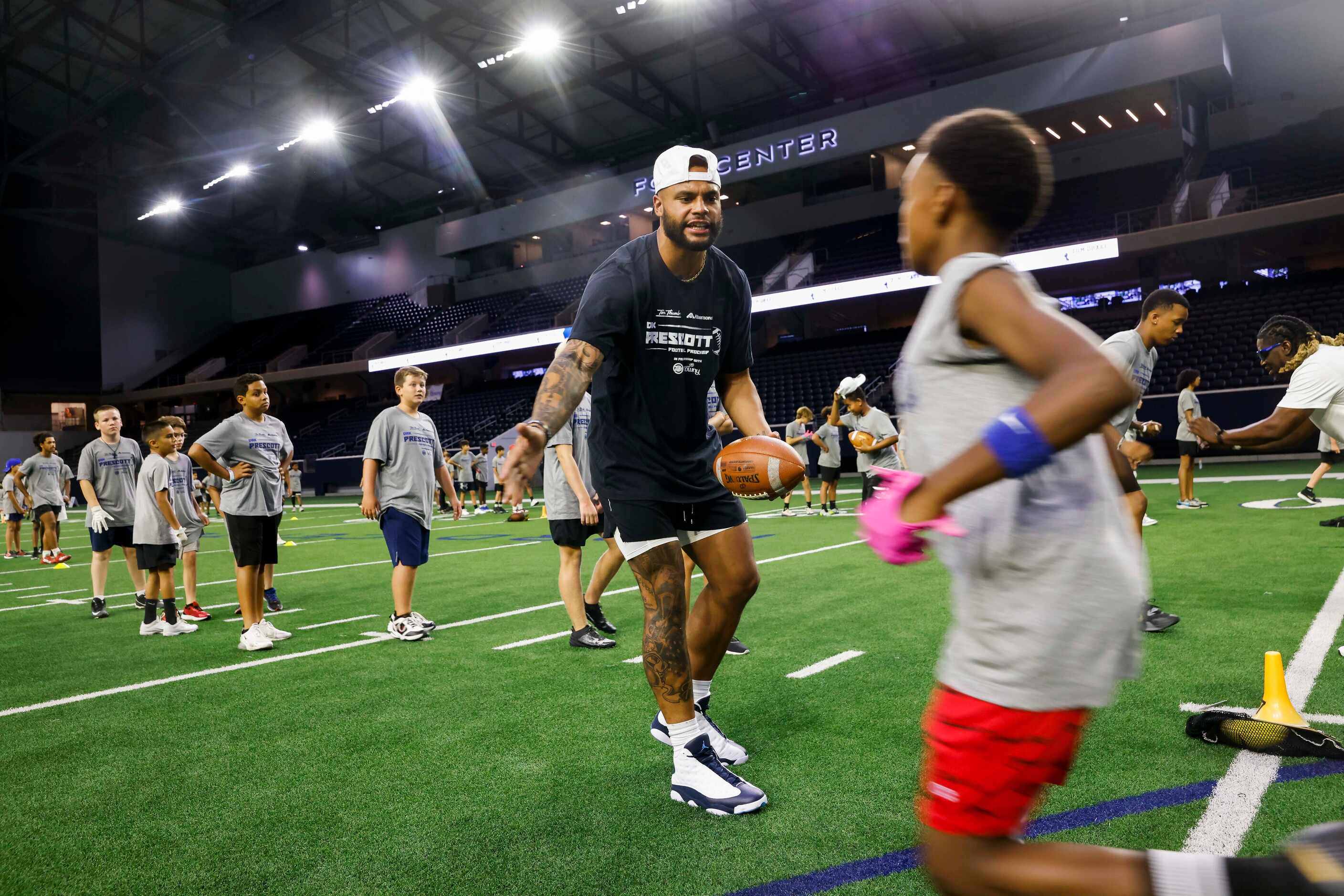Cowboys quarterback Dak Prescott high-fives a student while running drills with them during...
