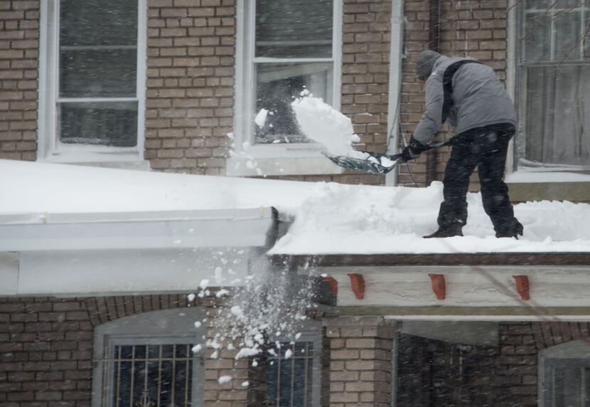  A man shovels snow off the roof of his porch during a snowstorm in Washington on January...