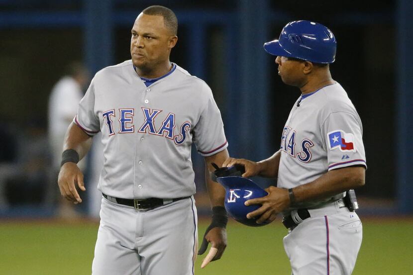 Texas Rangers third base coach Tony Beasley (27) talks with injured third baseman Adrian...